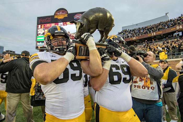 Iowa offensive lineman Ross Reynolds (59) and offensive lineman Keegan Render (69) lift the Floyd of Rosedale trophy at TCF Bank Stadium after last year's win over Minnesota.